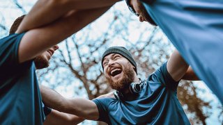 A happy, motivated group of friends supporting each other outdoors, representing encouragement and teamwork when quitting smoking.